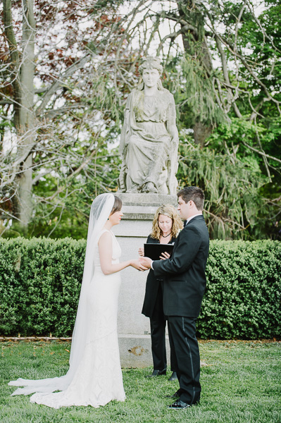 Bride and Groom reading vows in front of statue.
