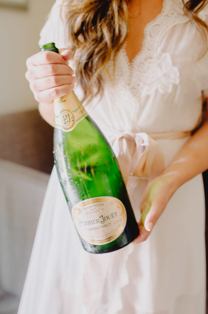 The bride gracefully holds a champagne bottle L Hewitt Photography

