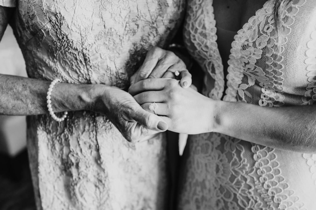 The bride's mother emotionally holds her daughter's hand, a tender moment filled with love and sentiment. L Hewitt Photography

