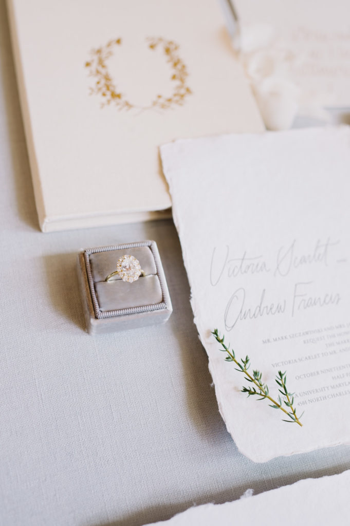 An exquisite wedding ring adorned with a sizable diamond, alongside an elegant wedding invitation. L Hewitt Photography

