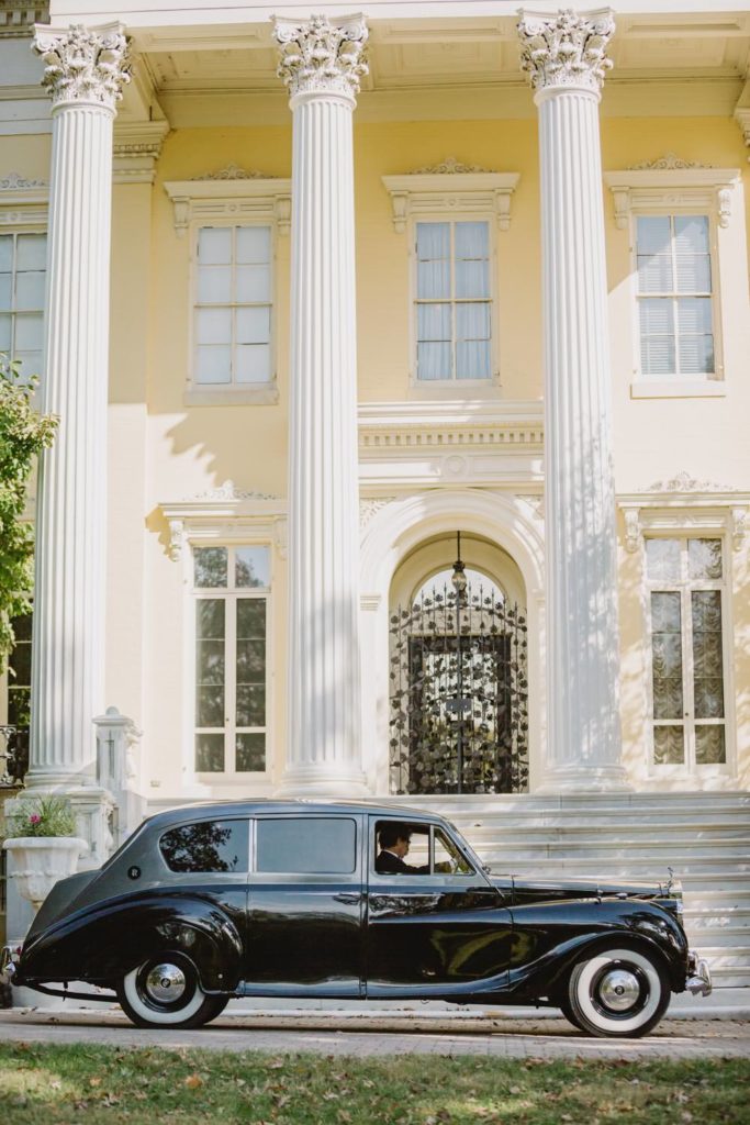 A classic wedding car drives in front of the Loyola Chapel, setting the scene for a timeless celebration. L Hewitt Photography

