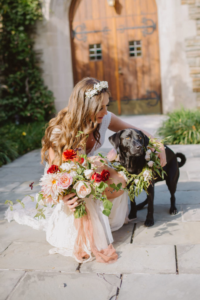 The bride embraces their pet dog, holding her bouquet in a heartwarming moment of love. L Hewitt Photography


