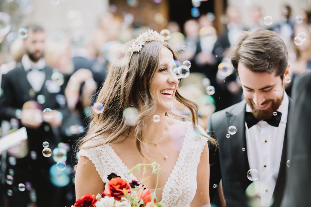 The bride and groom, enveloped in bubbles, share a moment of pure joy in their own world, resembling a fairy-tale. L Hewitt Photography

