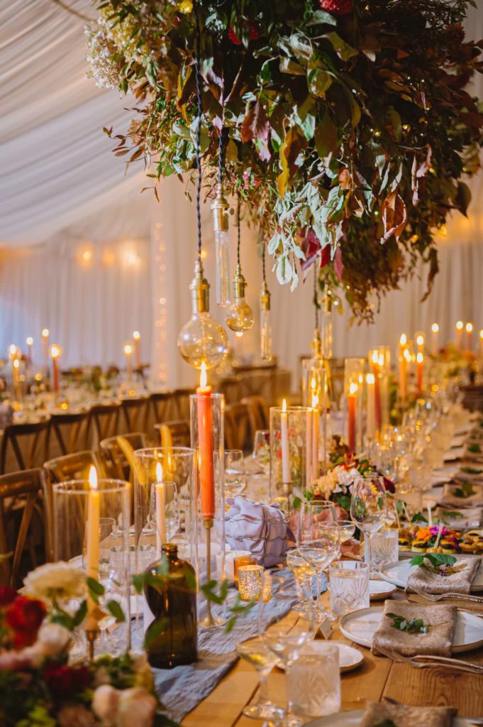 The wedding reception features long tables adorned with enchanting garden-inspired decorations, creating a magical ambiance. L Hewitt Photography

