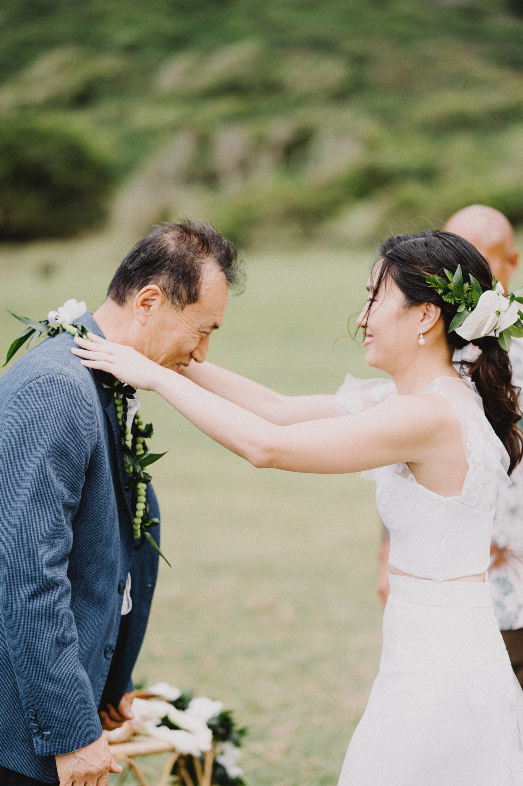 Tender moment as the bride places a lei on her father L Hewitt Photography