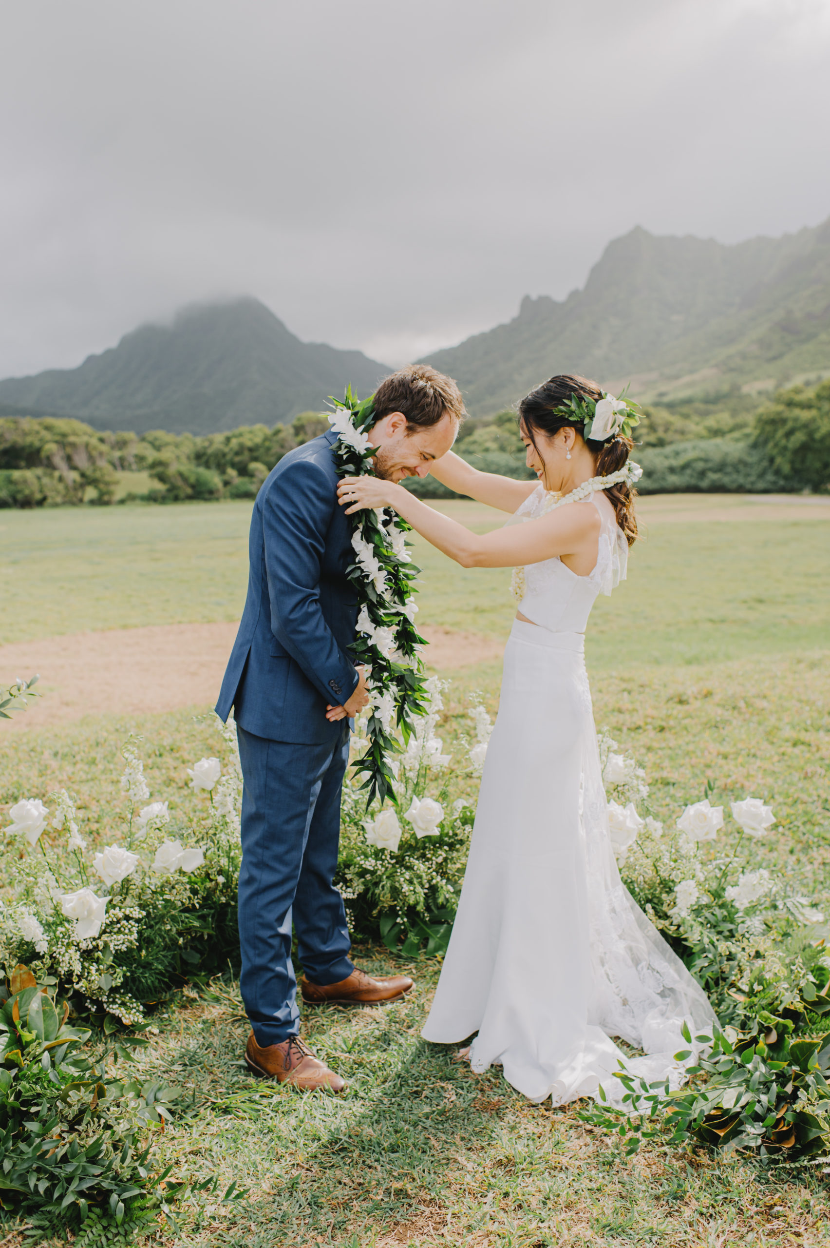 Heartfelt moment as the bride and groom exchange leis at Low Camp Kualoa Ranch L Hewitt Photography