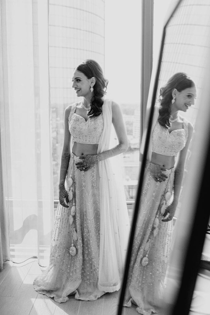 lovely bride getting ready for her Indian wedding reception donning a beautiful lehenga at Capital One Hall. L Hewitt Photography