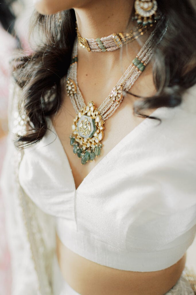 bride wearing silver white silk lehenga and jade, gold, and white necklace for her Indian wedding reception at Capital One Hall. L Hewitt Photography