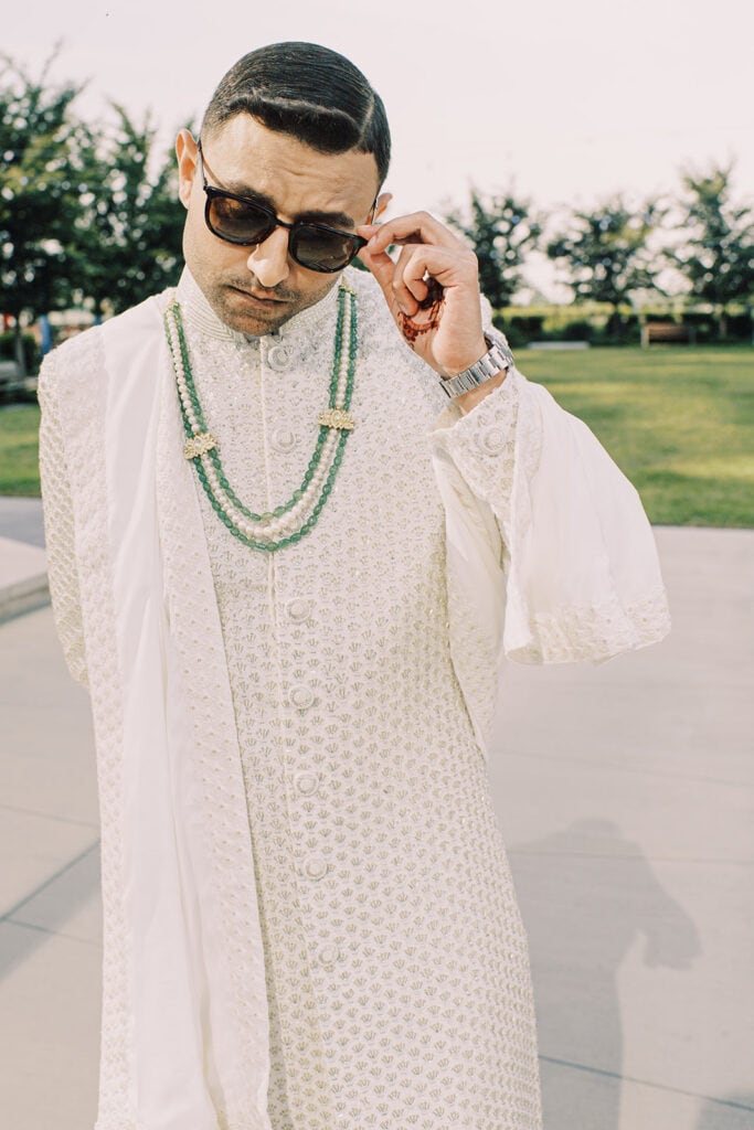 cool photo of groom wearing sunglasses and white sherwani for his Indian wedding ceremony at Capital One Hall. L Hewitt Photography