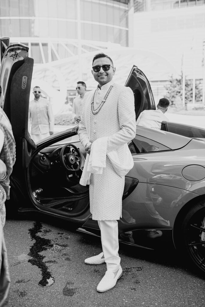 groom wearing sunglasses and white sherwani as he leaves for baraat for his Indian wedding ceremony at Capital One Hall. L Hewitt Photography