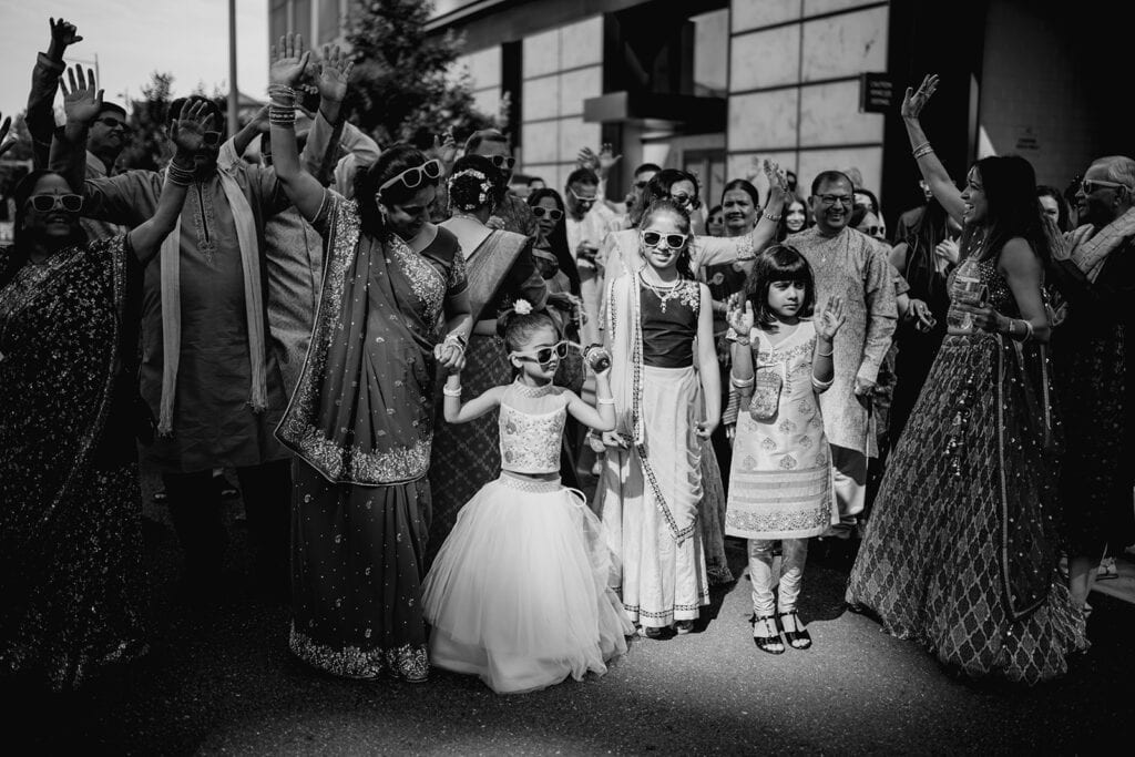 the family enjoying watching the festivities of the baraat for the Indian wedding ceremony at Capital One Hall. L Hewitt Photography
