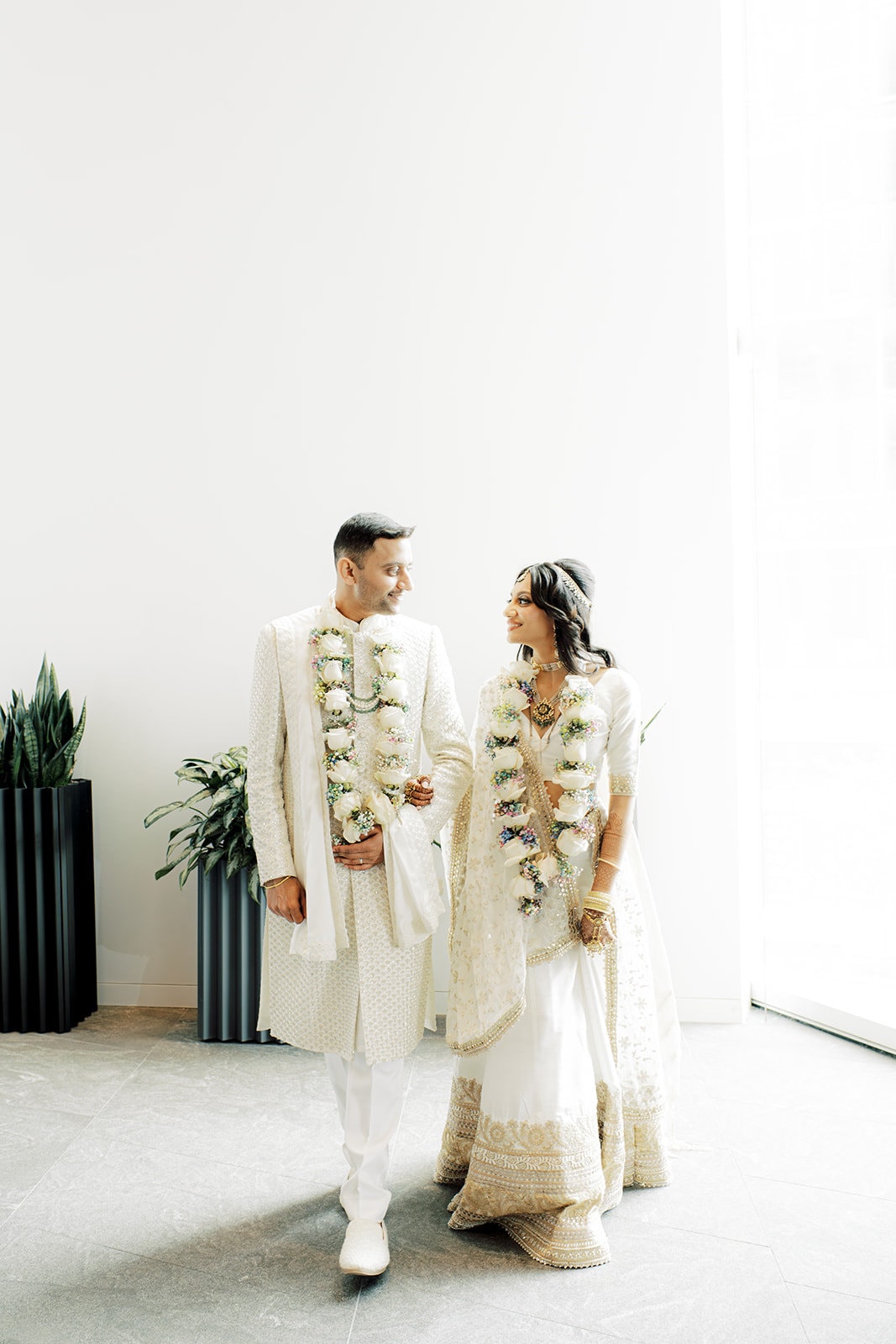 beautiful bride wearing a white silk lehenga and a handsome groom wearing sherwani for their Indian wedding ceremony at Capital One Hall. L Hewitt Photography