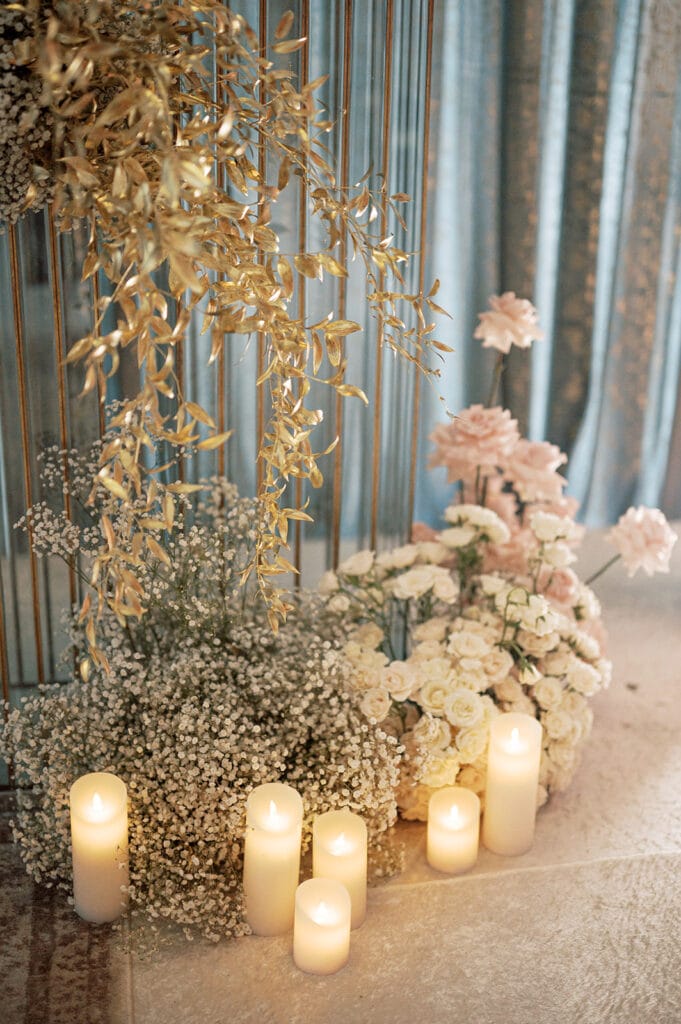 beautiful florals with baby’s breath, roses, and gold ruscus by Sarah Khan Event Styling with warm candles for the Indian wedding reception at Capital One Hall. L Hewitt Photography