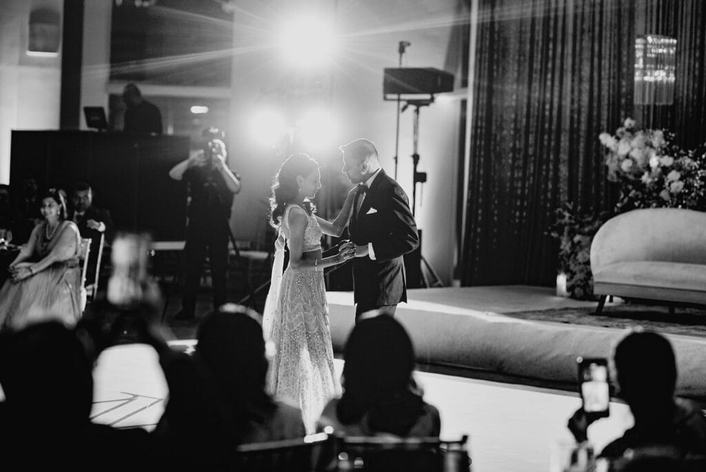 black and white first dance of the bride wearing a lavender evening dress and groom wearing a classic tuxedo at their Indian wedding reception at Capital One Hall. L Hewitt Photography
