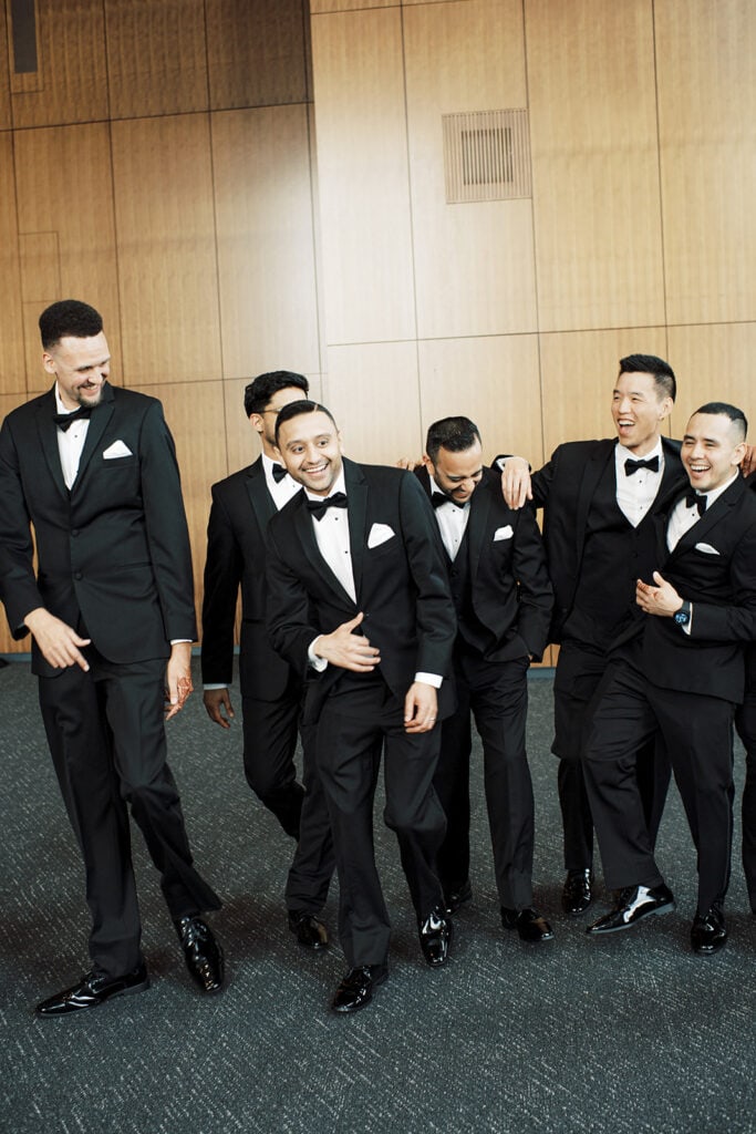 the groom with his groomsmen wearing a classic tuxedos for his Indian wedding reception at Capital One Hall. L Hewitt Photography