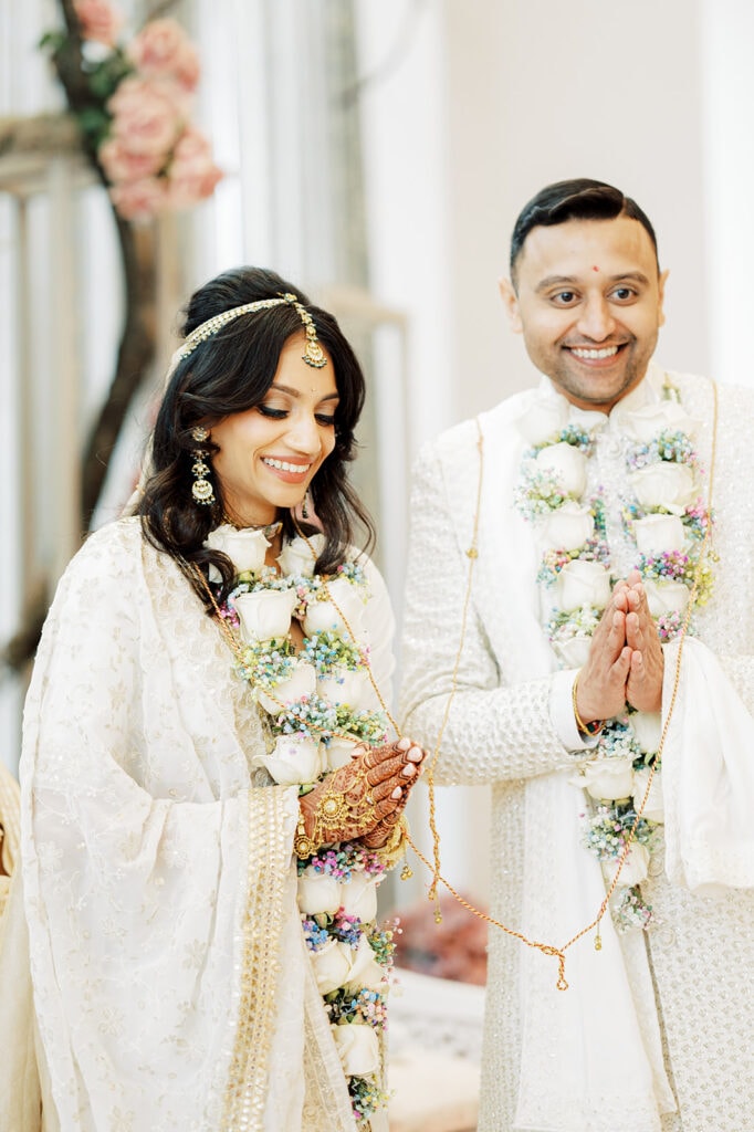 the bride wearing a silver white silk lehenga and the groom wearing a white sherwani thanks their guests after the garland exchange ceremony for their Indian wedding at Capital One Hall. L Hewitt Photography