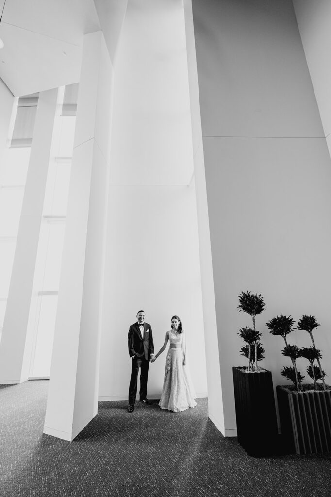 modern black and white architectural wedding portrait as the groom dons a classic tuxedo for their Indian wedding reception at Capital One Hall. L Hewitt Photography