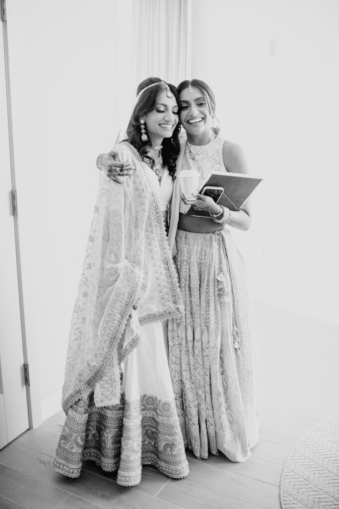 a joyful moment between the bride wearing a custom lehenga and her sister before her Indian wedding ceremony at Capital One Hall. L Hewitt Photography